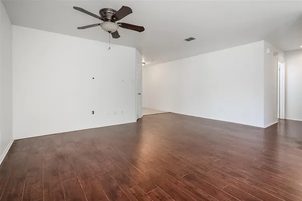 a view of a big room with wooden floor a ceiling fan and a window