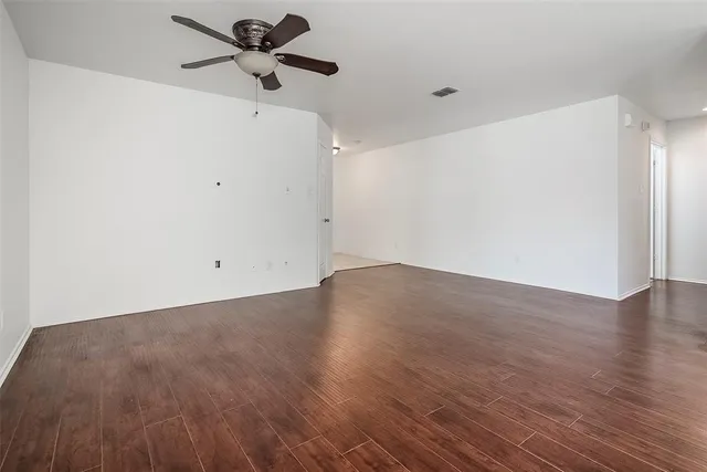 a view of a big room with wooden floor a ceiling fan and a window