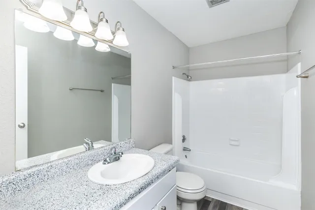 a bathroom with a granite countertop sink a toilet and shower
