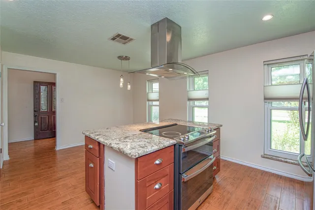 a kitchen with stainless steel appliances granite countertop wooden cabinets and wooden floor
