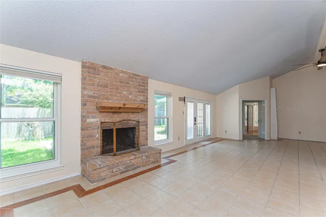 an empty room with windows and fireplace