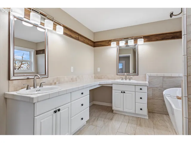 a spacious bathroom with a double vanity sink a mirror and a
