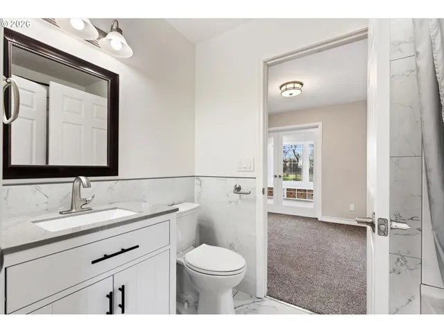 a bathroom with a toilet a sink a mirror and a shower