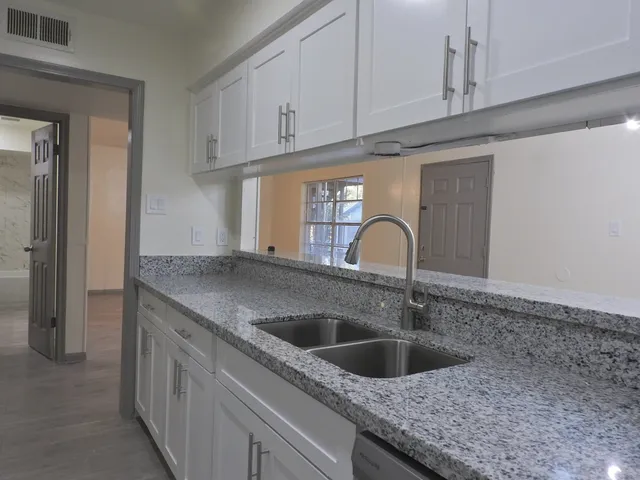 a kitchen with granite countertop a sink and cabinets