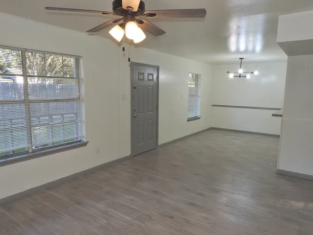 en empty room with windows and ceiling fan