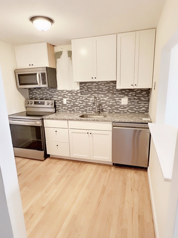 1039 Commonwealth Avenue, Unit 37 Boston, MA 02215 - Photo 2 of 7 a kitchen with stainless steel appliances granite countertop a stove a sink and white cabinets