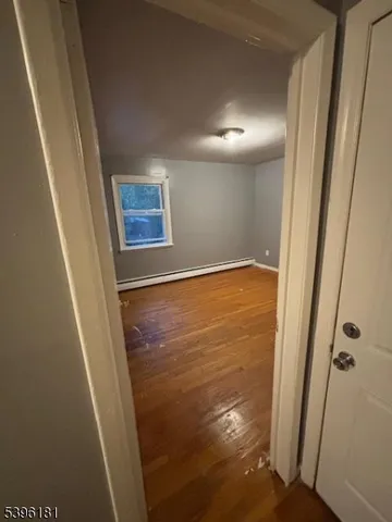 a view of a hallway with wooden floor and a bathroom