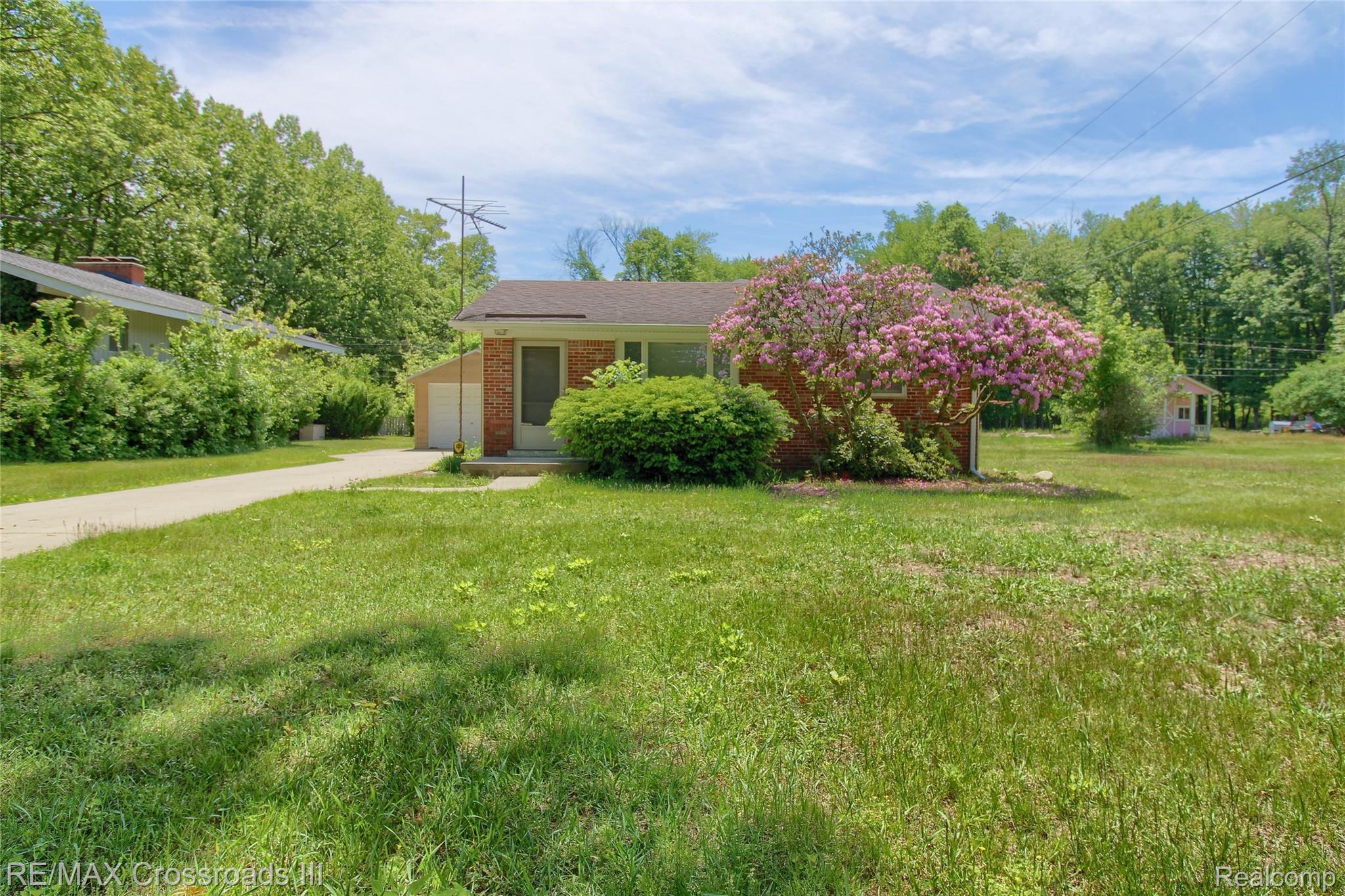 41509 Riggs Road Belleville, MI 48111 - Photo 1 of 26 Brick facade residence featuring mature landscaping with a flowering tree and a detached garage