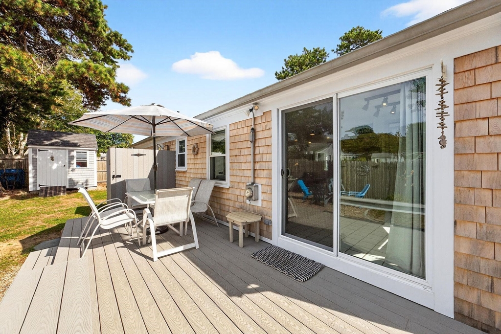 31 Easy Street Dennis, MA 02639 - Photo 28 of 41 a view of a patio with table and chairs under an umbrella with wooden floor