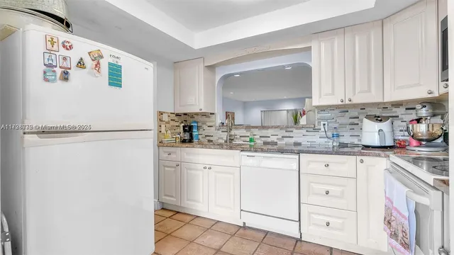 a kitchen with white cabinets and white appliances