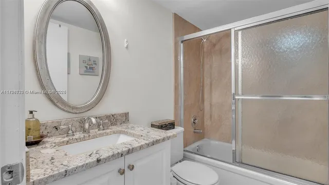 a bathroom with a granite countertop shower toilet and sink