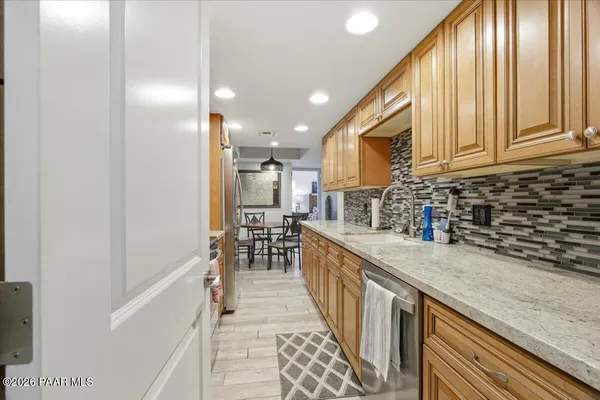 a kitchen with stainless steel appliances granite countertop a refrigerator a sink and a wooden cabinets