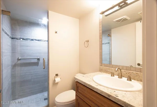 a bathroom with a granite countertop sink a toilet and shower
