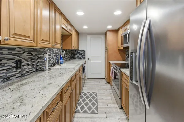 a kitchen with stainless steel appliances granite countertop a sink a stove and a refrigerator