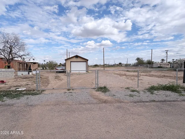a view of a dry yard with wooden fence