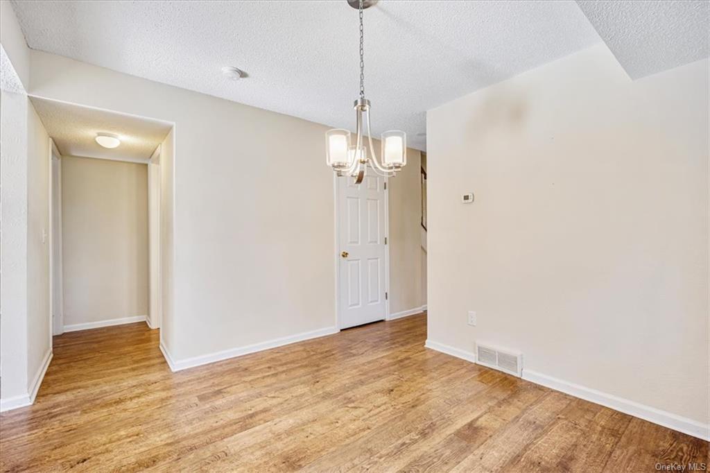 1 Chadwick Court Fishkill, NY 12524 - Photo 11 of 35 Unfurnished dining area with a textured ceiling, light wood-type flooring, and a notable chandelier