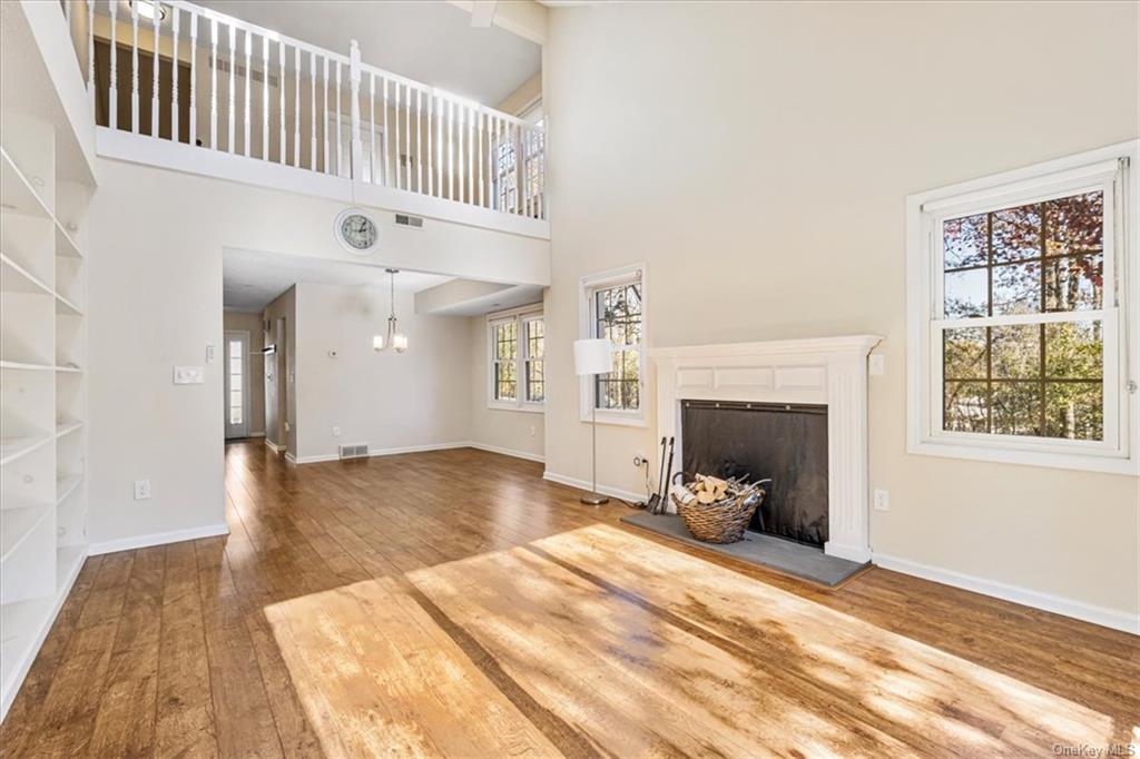 1 Chadwick Court Fishkill, NY 12524 - Photo 13 of 35 Unfurnished living room featuring a towering ceiling, a healthy amount of sunlight, and hardwood / wood-style flooring