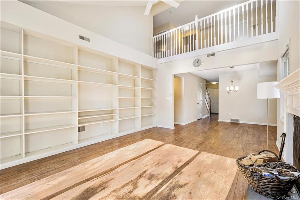 1 Chadwick Court Fishkill, NY 12524 - Photo 16 of 35 Unfurnished living room with a towering ceiling, hardwood / wood-style flooring, and a chandelier