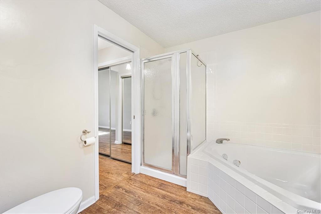 1 Chadwick Court Fishkill, NY 12524 - Photo 23 of 35 Bathroom with toilet, wood-type flooring, a shower with door, and a textured ceiling