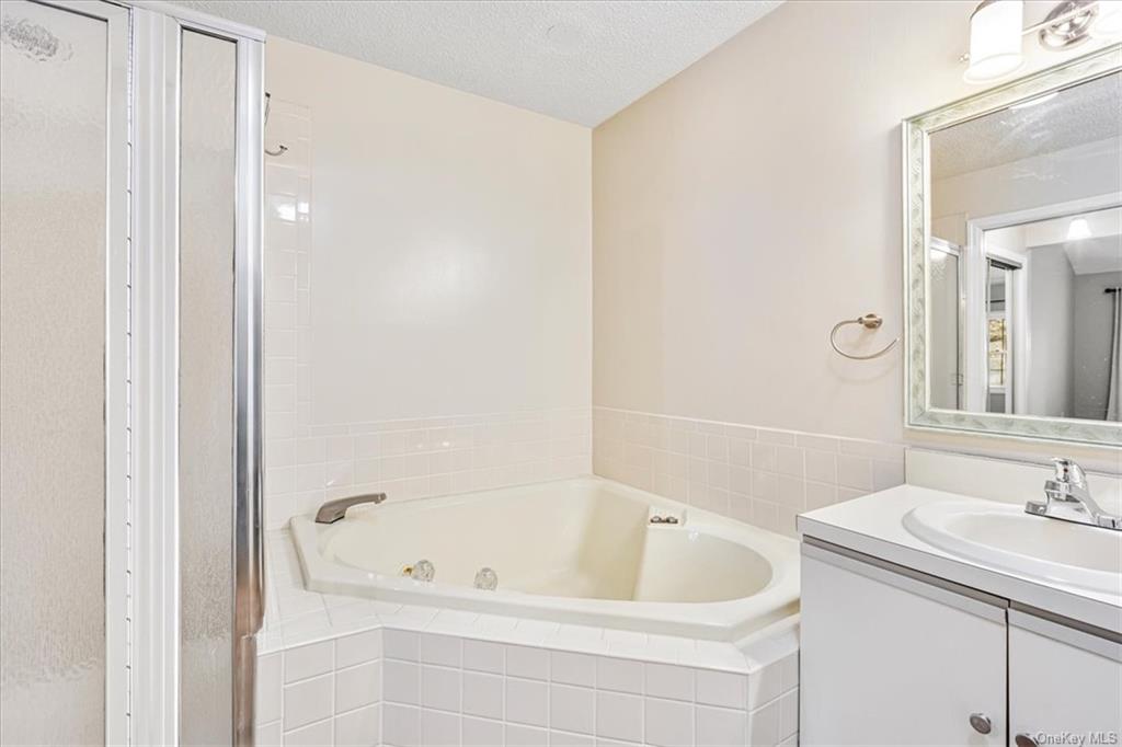 1 Chadwick Court Fishkill, NY 12524 - Photo 24 of 35 Bathroom with vanity, a textured ceiling, and tiled tub