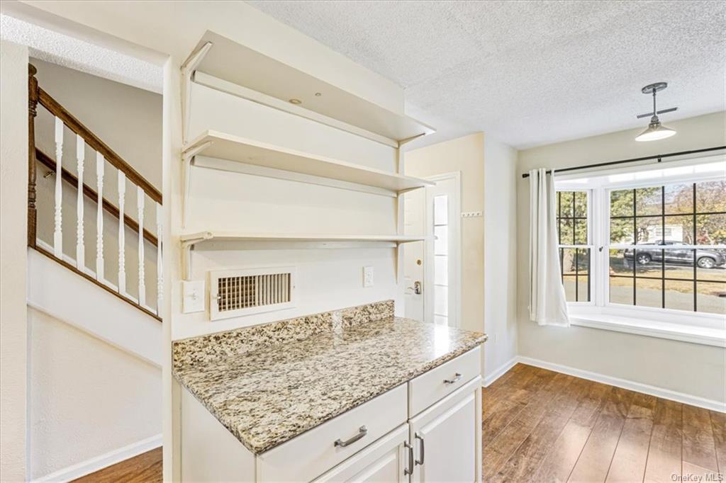 1 Chadwick Court Fishkill, NY 12524 - Photo 8 of 35 Kitchen featuring white cabinetry, a textured ceiling, light stone countertops, pendant lighting, and dark wood-type flooring