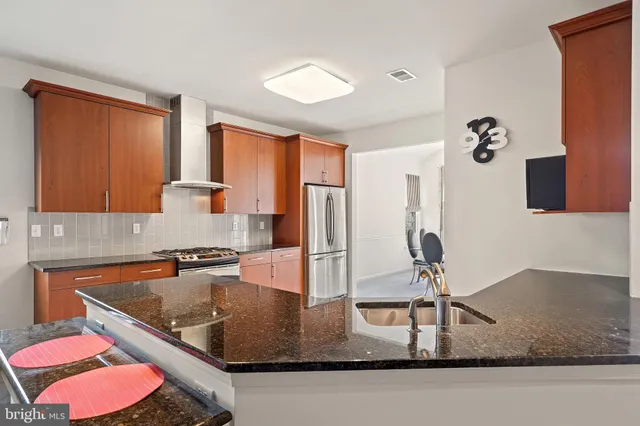 a kitchen with stainless steel appliances granite countertop a sink a stove and a refrigerator with wooden floor