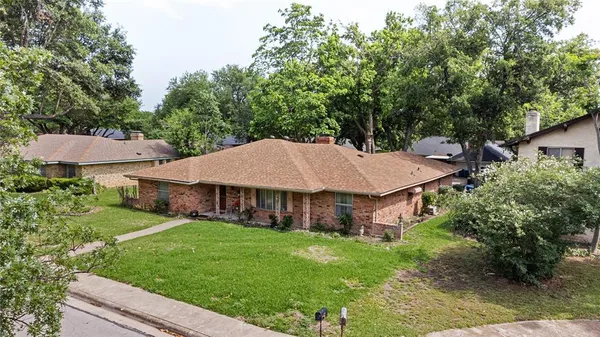 a view of a house with a big yard plants and large trees
