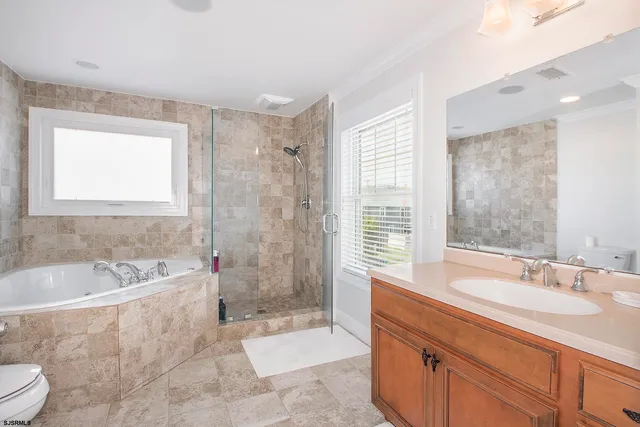 a spacious bathroom with a granite countertop sink a toilet a bathtub and shower