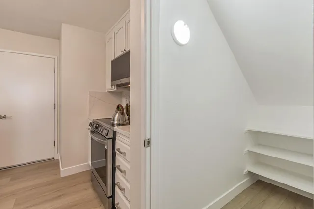 a view of a kitchen with fridge and wooden floor