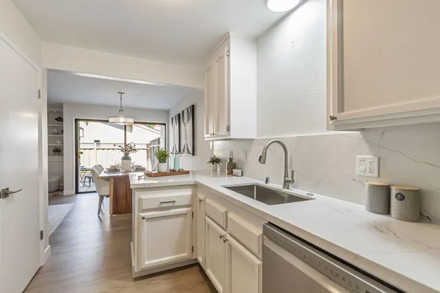 a kitchen with stainless steel appliances a sink dishwasher a stove and white cabinets with wooden floor