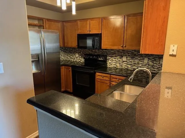 a kitchen with stainless steel appliances granite countertop a sink a stove microwave and refrigerator