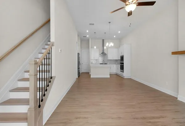 a view of a room with wooden floor staircase and a kitchen