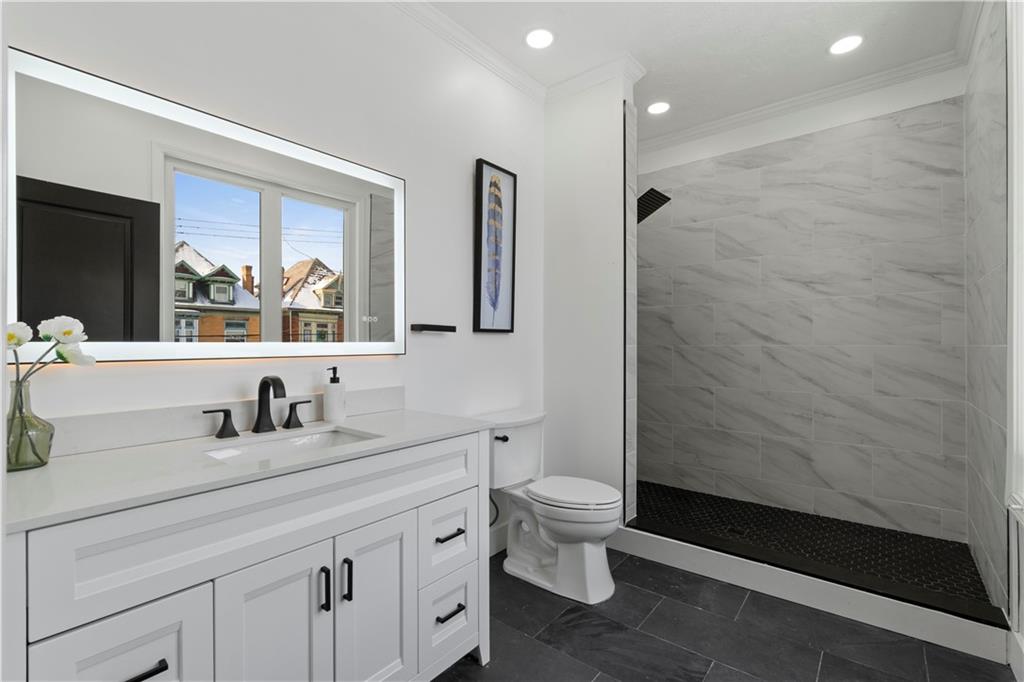 1105 Portland Street Pittsburgh, PA 15206 - Photo 24 of 48 a bathroom with a toilet a sink a mirror a vanity and shower