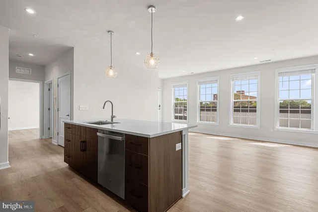 a kitchen with stainless steel appliances granite countertop a sink a stove and a wooden floor