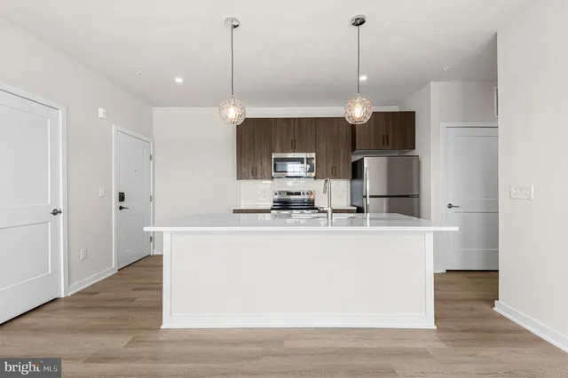 a view of a kitchen with kitchen island stainless steel appliances sink and refrigerator