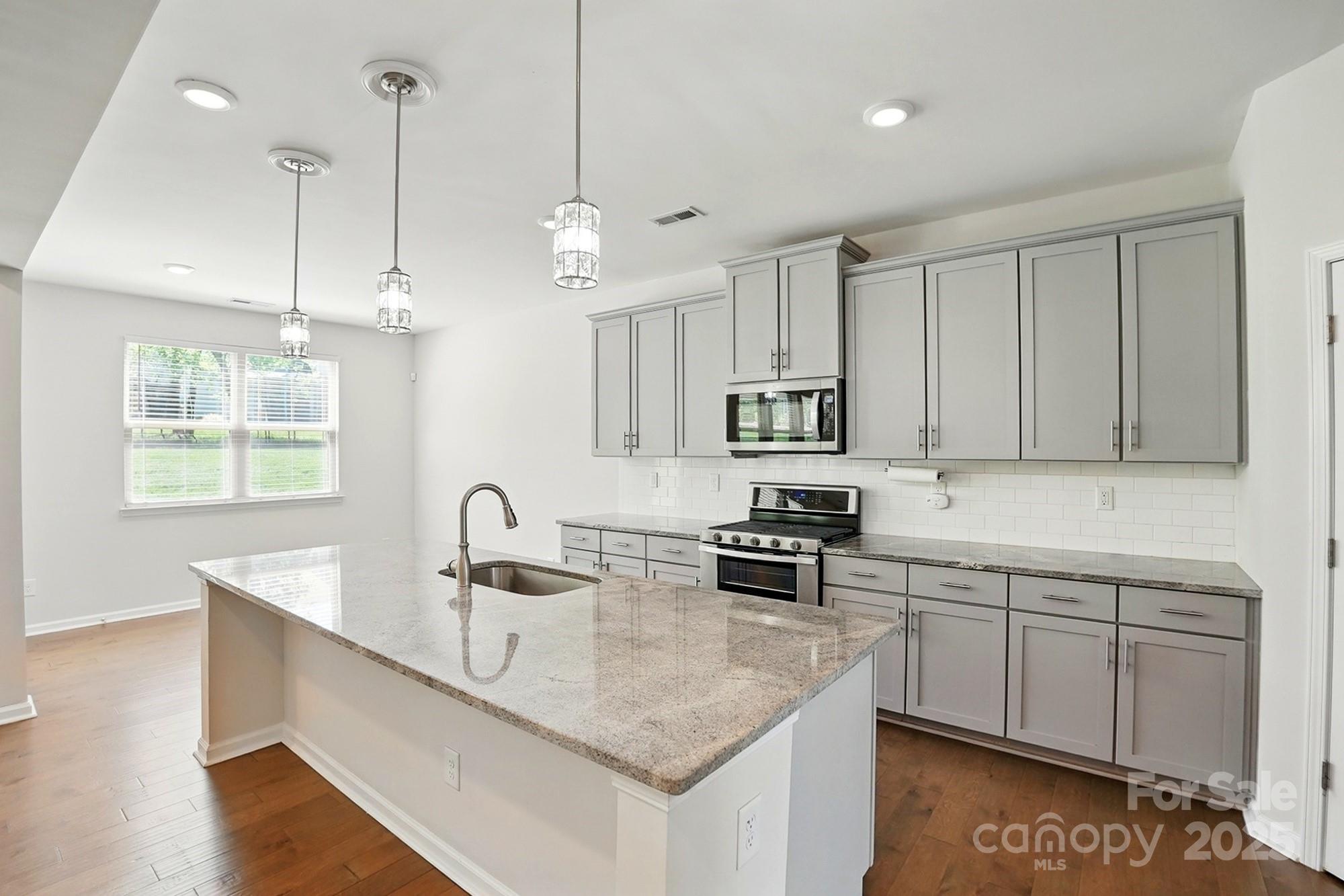 20422 Creek Bend Edge Court Matthews, NC 28105 - Photo 7 of 39 a kitchen with stainless steel appliances granite countertop a sink a stove a microwave a center island and cabinets