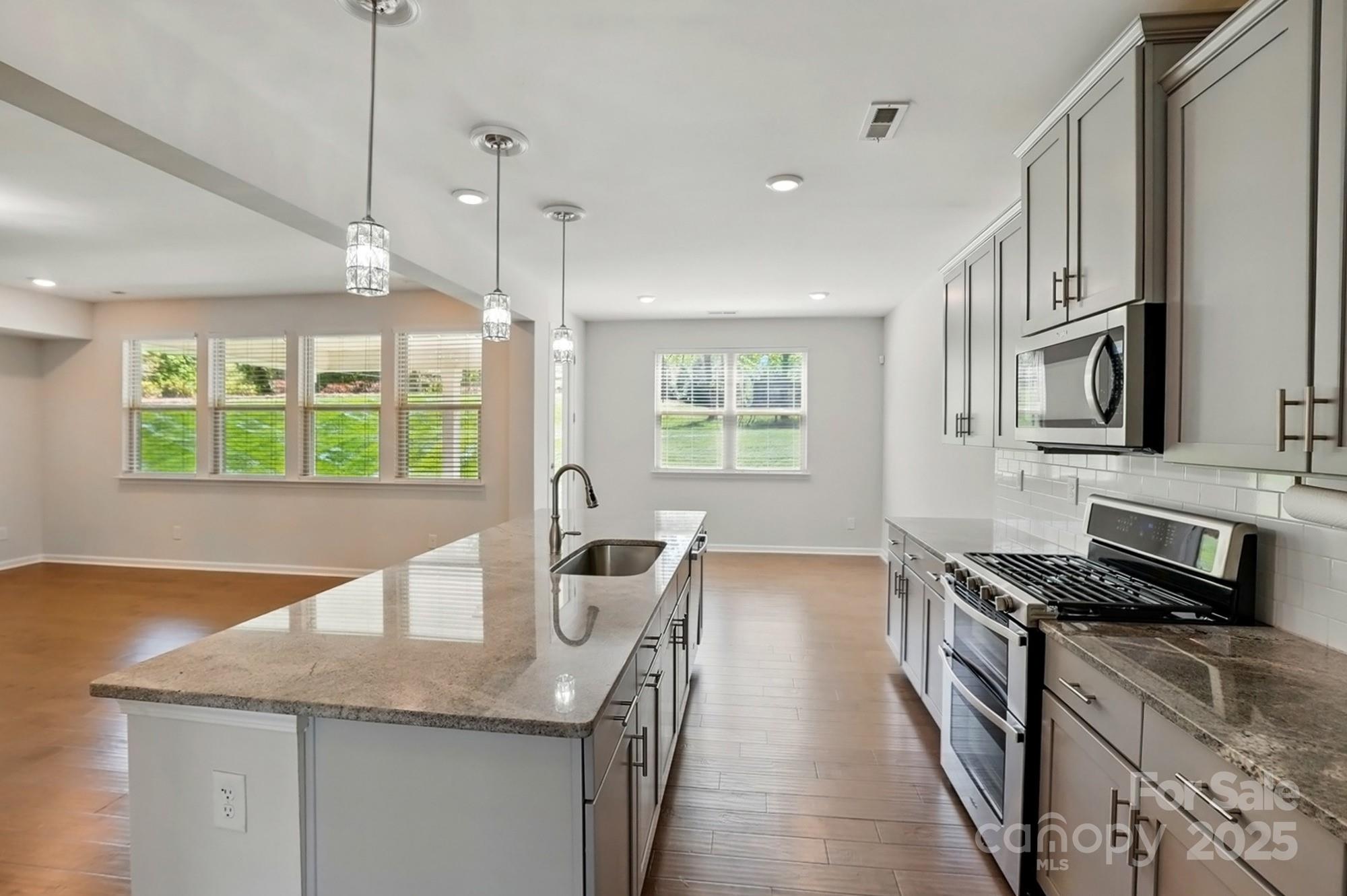 20422 Creek Bend Edge Court Matthews, NC 28105 - Photo 9 of 39 a kitchen with kitchen island granite countertop a stove a sink and a counter top space