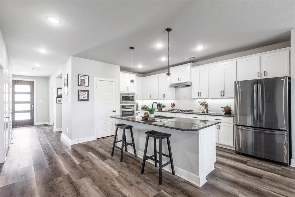905 Bent Brook Road Little Elm, TX 75068 - Photo 11 of 40 a kitchen with stainless steel appliances granite countertop a table chairs stove refrigerator and cabinets