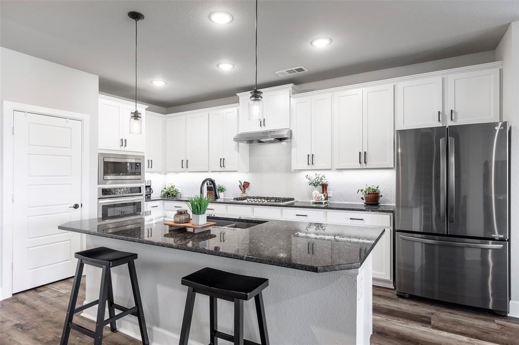 905 Bent Brook Road Little Elm, TX 75068 - Photo 12 of 40 a kitchen with stainless steel appliances granite countertop a refrigerator a sink dishwasher a stove and white cabinets with wooden floor