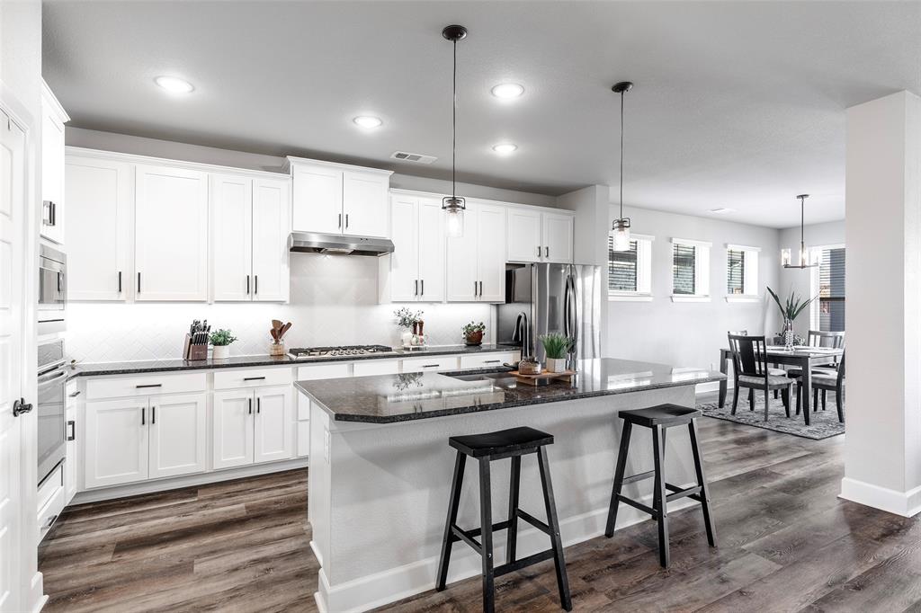 905 Bent Brook Road Little Elm, TX 75068 - Photo 9 of 40 a kitchen with stainless steel appliances kitchen island granite countertop a table chairs sink and cabinets