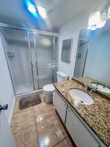 a bathroom with a granite countertop sink a mirror and shower