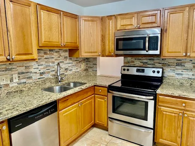 a kitchen with granite countertop a stove top oven microwave and cabinets