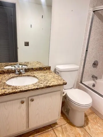 a bathroom with a granite countertop toilet sink and shower