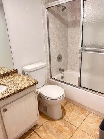 a bathroom with a granite countertop bathtub shower and toilet