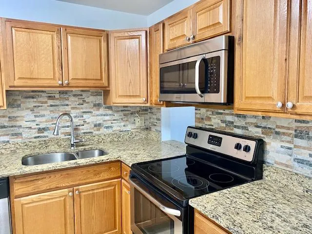 a kitchen with stainless steel appliances granite countertop a sink stove and microwave