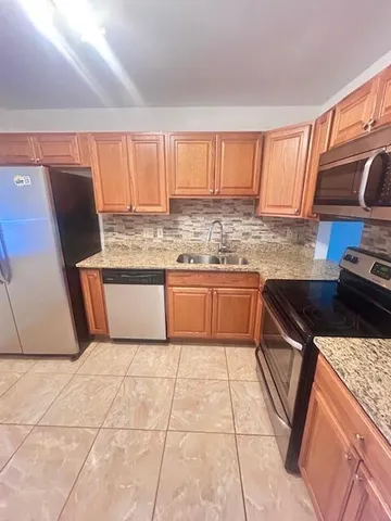 a kitchen with stainless steel appliances granite countertop a stove a sink and a microwave