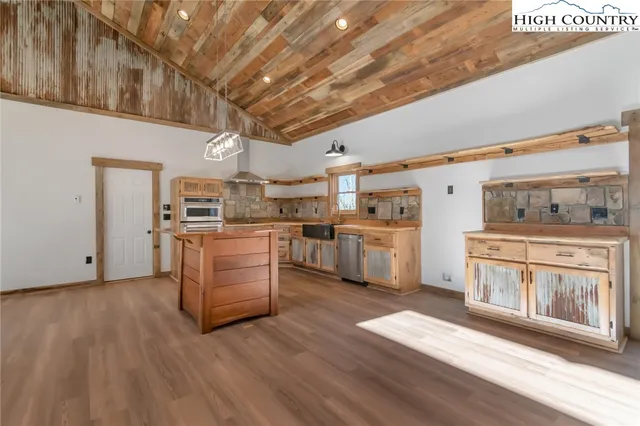 a living room with stainless steel appliances furniture a rug and a kitchen view