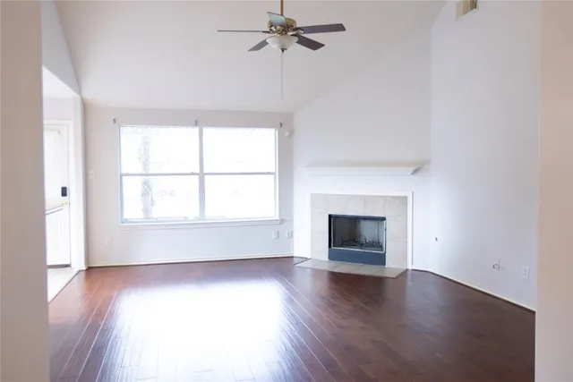 an empty room with wooden floor windows and fireplace