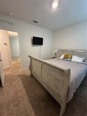 a bedroom with a bed and a flat tv screen on dresser
