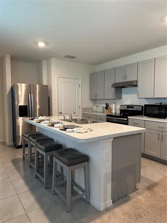 a kitchen with stainless steel appliances granite countertop a table chairs sink refrigerator and cabinets